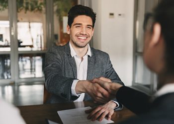Business, career and placement concept - happy caucasian man 30s rejoicing and shaking hands with employee when was recruited during interview in office